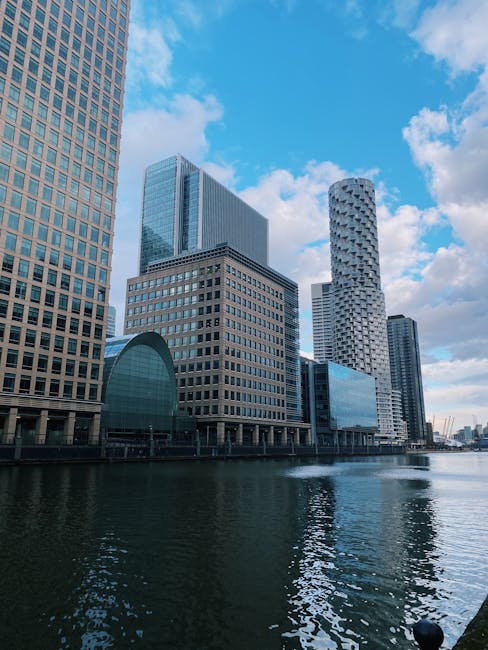 A panoramic view of a city skyline featuring modern high-rise office buildings and residential towers constructed mainly from glass and steel, with some under ongoing development. Prominent constructi